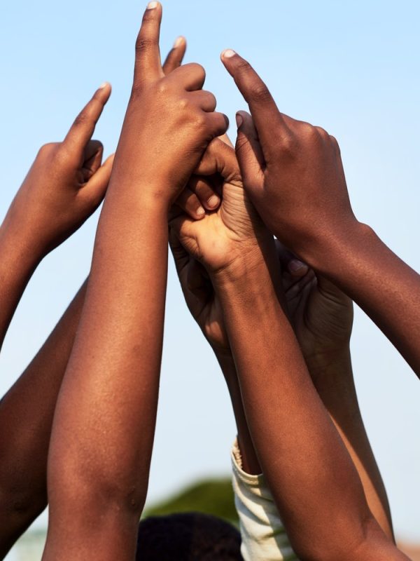 youthful-hands-raised-together-toward-a-blue-sky